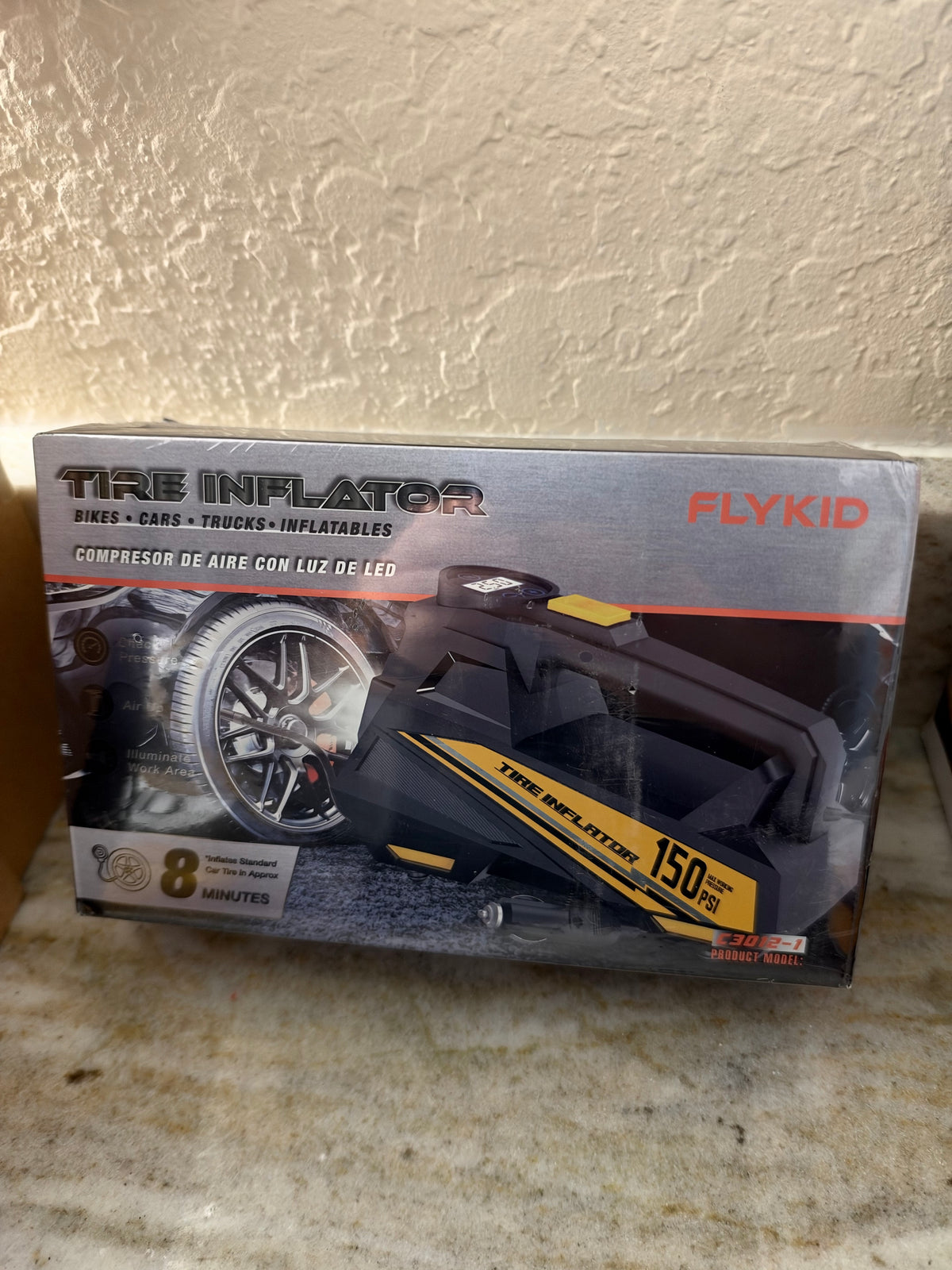 FlyKID tire inflator with digital display and air hose, compact portable device for inflating vehicle tires.