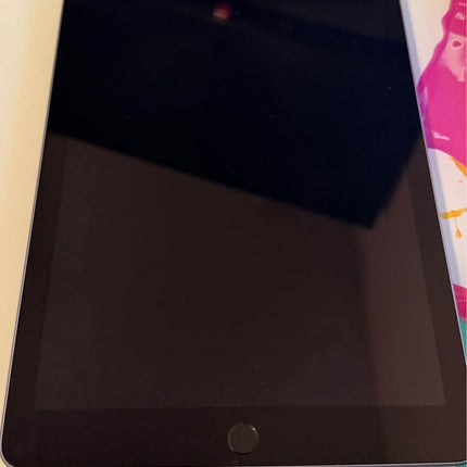 Apple iPad 6th Generation 128GB tablet showing the screen and sleek design in a natural setting.