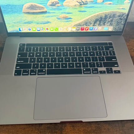 Apple 16-inch MacBook Pro in Space Gray with Touch Bar, open on a desk showing the keyboard and screen.