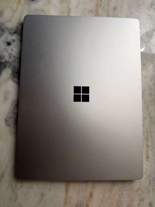 Microsoft Surface Laptop Go showing the sleek silver laptop open with keyboard and screen visible.